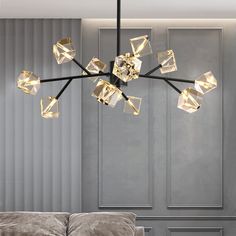 a modern chandelier hanging from the ceiling in a living room with grey walls