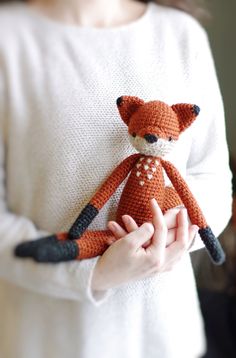 a person holding a stuffed animal in their hands and wearing a white shirt with a red fox on it