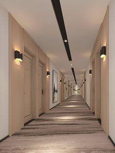 an empty hallway with several doors and lights on either side of the corridor is lit by recessed lighting