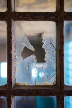 a broken glass window with the reflection of another building in it's center piece