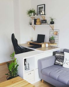 a living room with a couch, desk and shelves on the wall next to it