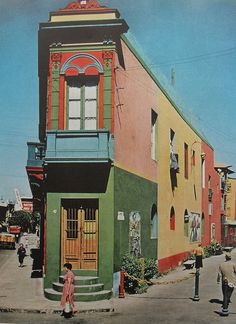 an old photo of people walking in front of a colorful building