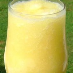 a glass filled with yellow liquid sitting on top of a green field