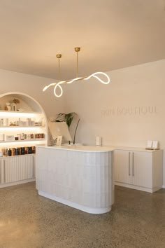 the interior of a skin boutique with white counter tops and lights above it, along with shelving