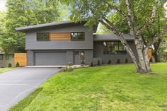 a large gray house sitting on top of a lush green field next to a tree