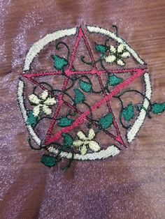 a close up of a piece of cloth with flowers on it and a pentagram