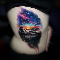 the back of a woman's stomach with an image of mountains and stars on it