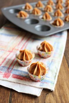 small cupcakes with peanut butter frosting on a napkin next to a muffin tin