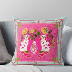 a pink pillow with two dogs and flowers on it sitting on a couch next to pillows