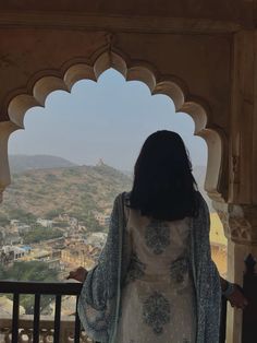 a woman standing in front of an arch looking out at the city