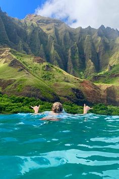 two people swimming in the ocean with mountains in the background