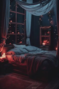 a bed in a dark room with candles on the floor and curtains hanging over it