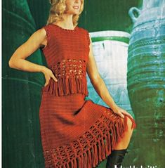 a woman in a red crocheted dress and black boots posing for a photo