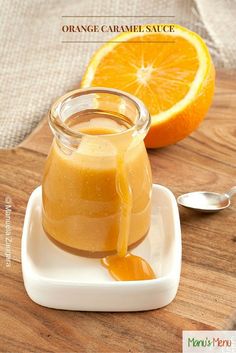 an orange caramel sauce in a glass jar on a white plate with spoons