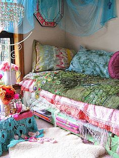 a bed with lots of pillows on top of it next to a wall hanging from the ceiling