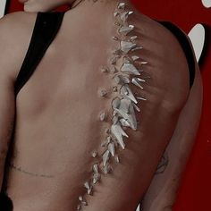 the back of a woman's body with white flowers on it, and tattoos