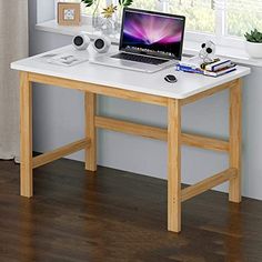 a laptop computer sitting on top of a white desk in front of a windowsill