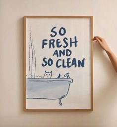 a person holding up a framed poster with a cat in a bathtub that says, so fresh and so clean