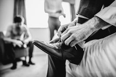 two people are sitting in chairs and one person is tying his shoes while the other man watches