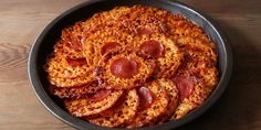 pepperoni pizza in a black bowl on a wooden table with wood grained surface