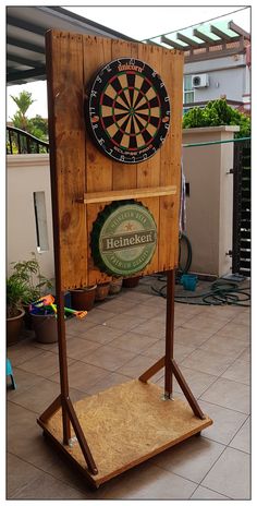 a wooden sign with a dart on it in front of a building and some potted plants