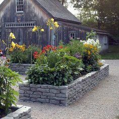 a stone planter with flowers in front of a barn