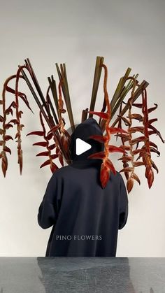 a person wearing a hoodie with plants growing out of his head on top of a table