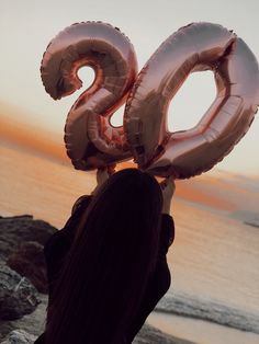 a woman holding up two large balloons in the shape of the number 30 on top of her head