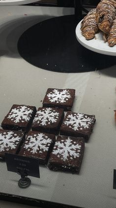 chocolate brownies and cookies are on display in a store window with snowflakes