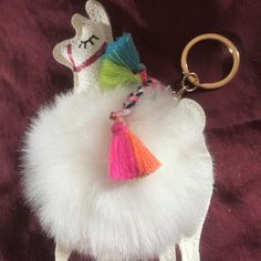 a llama keychain with tassels on it sitting on a purple blanket