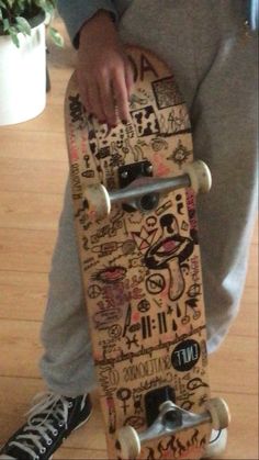 a person sitting on the floor holding a skateboard with stickers all over it