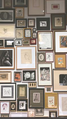 a wall full of framed pictures and drawings