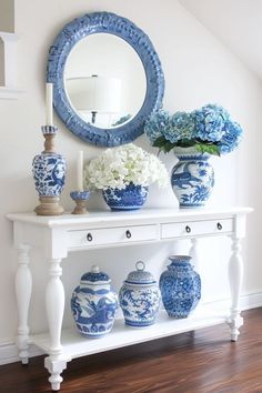 blue and white vases sit on a shelf in front of a round mirror, with an oval mirror above it