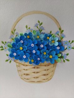 a basket filled with blue flowers on top of a white wall