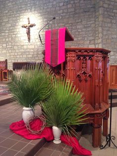 a church alter with two plants in the foreground and a red cloth on the ground