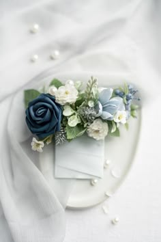 a white plate topped with blue flowers and greenery