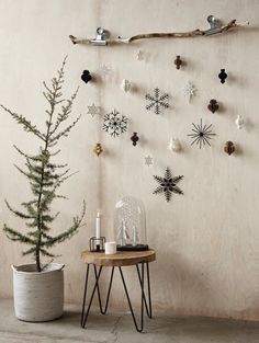 a small christmas tree in front of a wall with snowflakes and stars on it