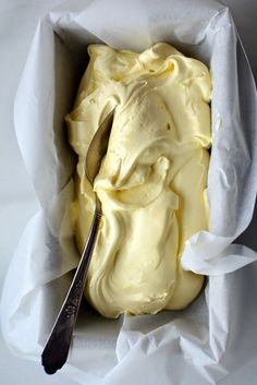 a spoon in a white container filled with yellow frosting