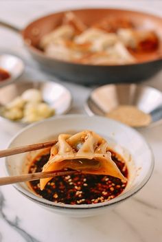 chopsticks in a bowl filled with food on a marble counter top next to other bowls