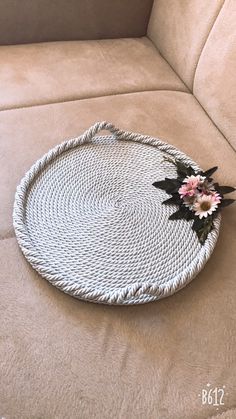 a white wicker tray with pink flowers on it sitting on a tan couch cushion