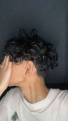 a man with curly hair covering his face