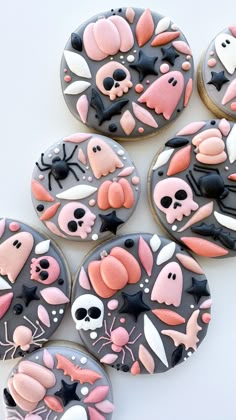 some decorated cookies are sitting on a table with black and pink frosted icing