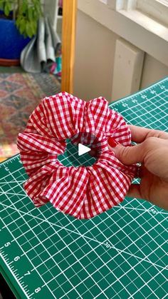 someone is holding a red and white flower on a green cutting board