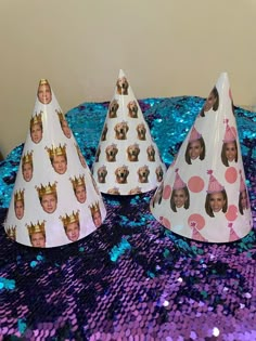 three party hats with pictures of children's faces are on a purple and blue sequin tablecloth