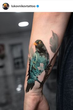 a person with a tattoo on their arm holding a bird in the air and trees