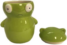 a green ceramic frog planter with eyes on it's face next to a bowl