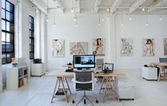 an office with multiple desks and chairs in front of two monitors on the wall