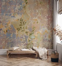 a bed sitting in front of a window next to a wall covered in peeling paint