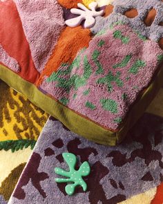 a green brooch sitting on top of a pile of purple and orange towels with flowers