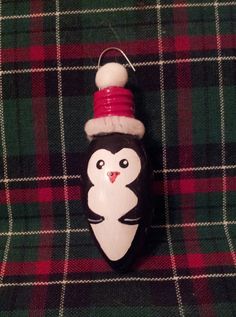 a penguin ornament with a santa hat on it sitting on a plaid blanket